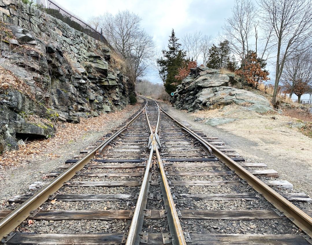 Photo by Lance Grandahl brown metal train rail near rocky mountain during daytime